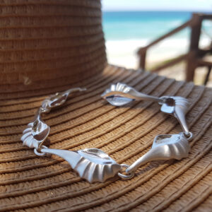 Beautifully sculpted Murex bracelet by Daniel Bentley sitting on summer hat.
