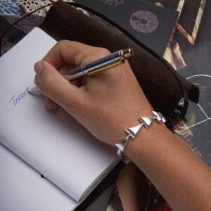 rident Bracelet in sterling silver worn on a model’s hand while writing, Daniel Bentley Jewellery.