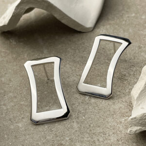 Deanna Earrings in polished sterling silver, resting on a natural stone background. Simple, refined design inspired by Greek architecture, highlighting the smooth polished finish.