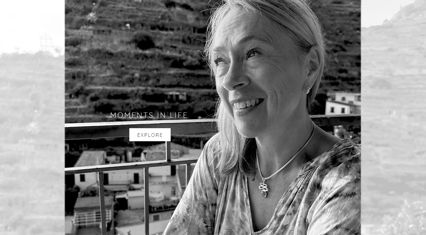 Woman wearing a Daniel Bentley pendant during a quiet moment overlooking a hillside village.